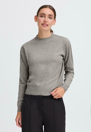 Grå genser med lange ermer og rund hals, tettsittende i livet, laget av et mykt, lett materiale, kombinert med svarte bukser.