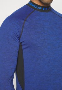Sportshirt met lange mouwen in gemêleerd blauw, voorzien van een zwarte kraag met blauw logo, een gladde textuur en contrasterende zwarte zijpanelen.