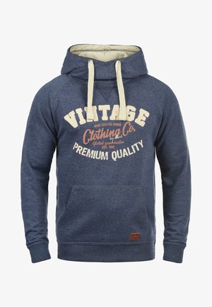 Mørkeblå hoodie med en cremefarvet foret hætte, frontlomme og ribbede manchetter. Har vintage-inspireret skrift i hvid og fersken.