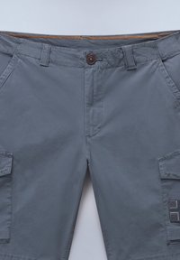 Gray cargo shorts with a button closure, four pockets, and textured accents. Made of lightweight fabric with contrasting orange stitching.