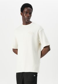 White ribbed cotton T-shirt with short sleeves, featuring a small beige embroidered logo on the chest and a relaxed fit.