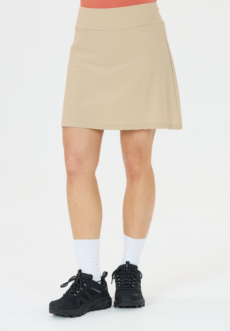 Beige, leichtgewichtiger Rock mit glatter Textur, kombiniert mit schwarzen Sportschuhen und weißen Kniestrümpfen. Der Rock hat ein gerades Schnittdesign.