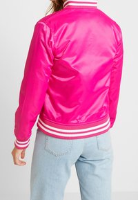 Pink satin bomber jacket featuring a ribbed collar and cuffs in contrasting white and pink stripes. Smooth texture with a fitted silhouette.