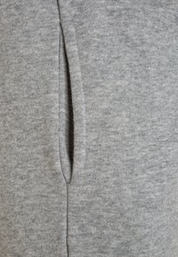 Harmaa collegekangas, jossa on sileä pinta ja sivusaumareikä. Materiaali näyttää lämpimältä ja kevyeltä, ja siinä on heather-kuvio.