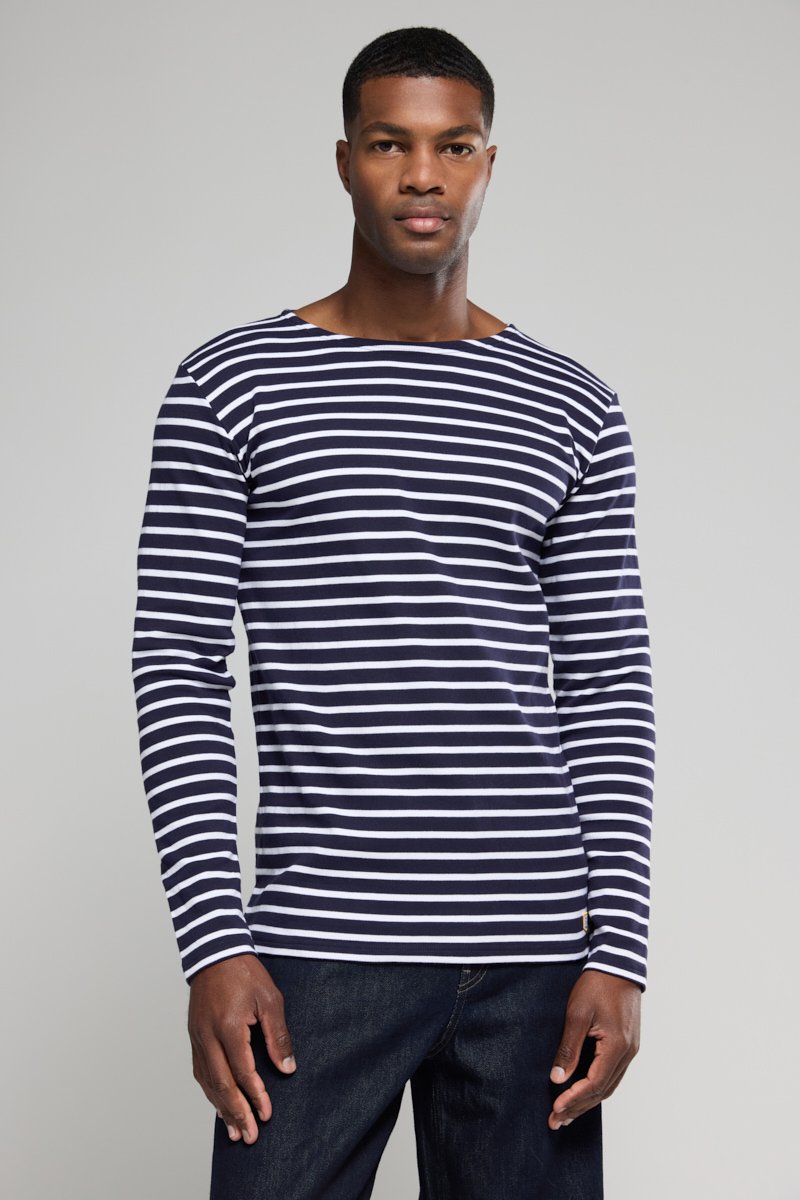 Marineblau-weiß gestreiftes Langarmshirt mit Bootsausschnitt, aus weichem Material, kombiniert mit dunklen Jeans. Auffällige horizontale Streifen.
