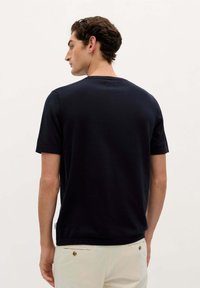 Marineblå kortærmet t-shirt lavet af blød stof, med rund halsudskæring og opkrøllede ærmer, med et lille logo-tag i kanten.