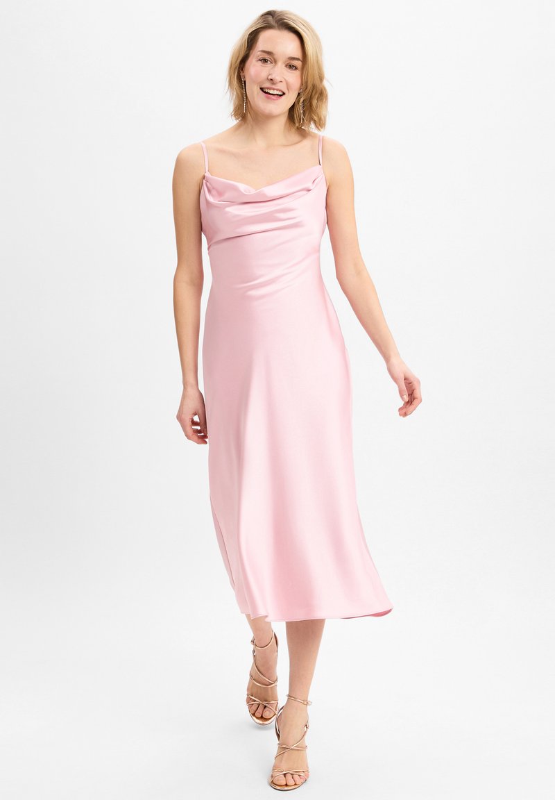 Roze satijnen jurk met een kraag, mouwloos, midi lengte, rechte silhouet, zijsplit en een gladde textuur. Gecombineerd met sandaaltjes met bandjes.