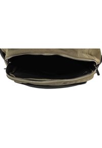 Sac à dos en toile vert olive avec un fond noir. Il possède une grande ouverture zippée et une doublure intérieure lisse pour un accès facile.