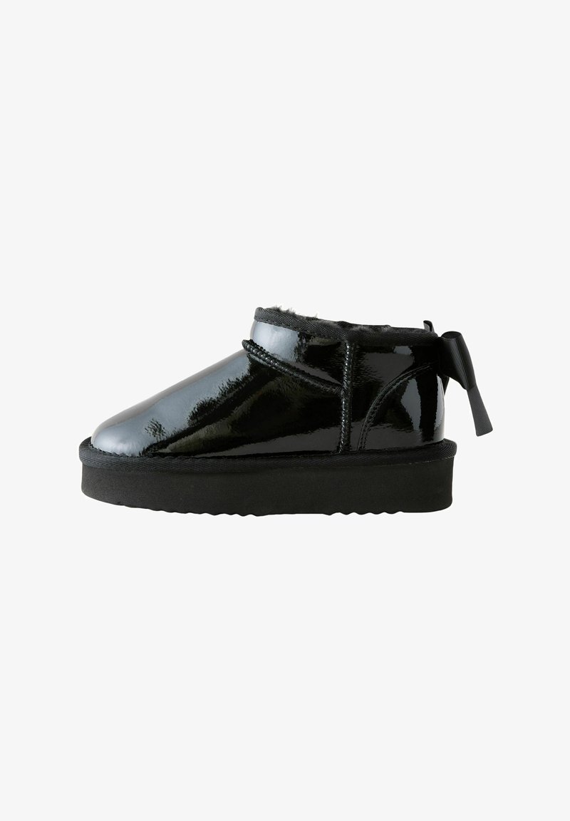 Stivaletto nero lucido alla caviglia con suola spessa, fodera interna morbida, cuciture laterali e nastro decorativo ad anello sul retro.