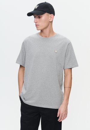 Gray t-shirt made of soft fabric, featuring a crew neck and short sleeves. Includes a small logo on the left chest and is paired with black pants.