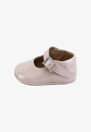 Zapato de bebé rosa con superficie brillante y correa asegurada por una hebilla adornada con strass, forro interior suave en marrón, aislado sobre fondo blanco.