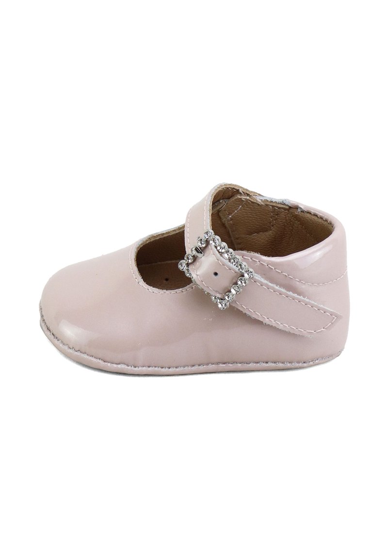 Zapato de bebé rosa con superficie brillante y correa asegurada por una hebilla adornada con strass, forro interior suave en marrón, aislado sobre fondo blanco.