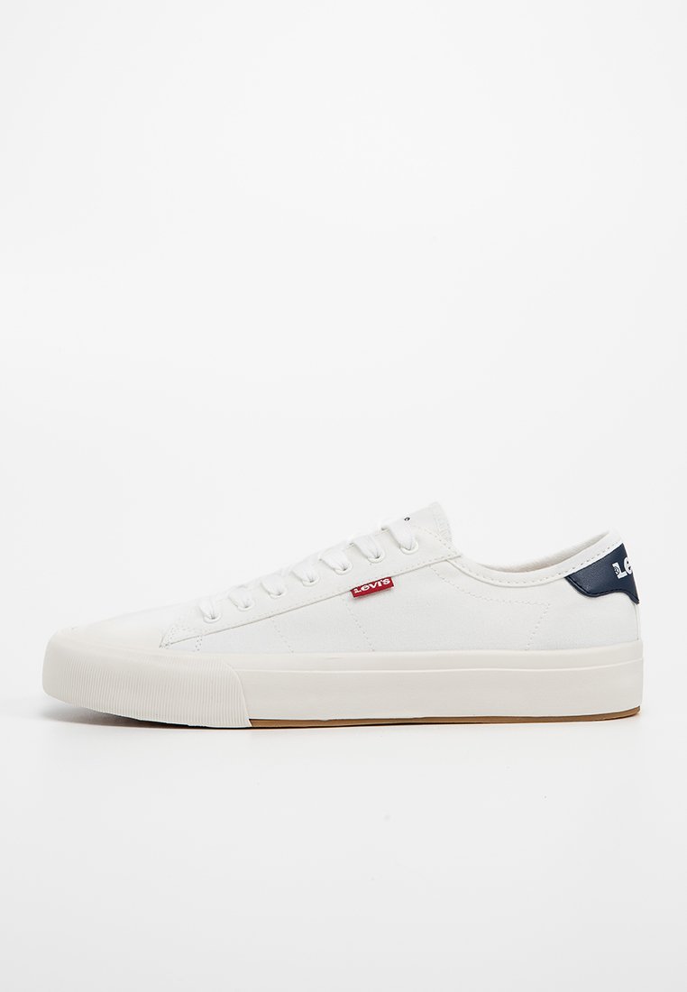 Zapatilla de lona blanca con suela de goma, que presenta un acento en azul marino en el talón y un pequeño logo de Levi's en rojo en el lateral. Diseño de punta redonda y cordones.