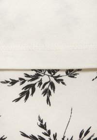 Witte stof met een zwart botanisch motief, featuring delicate bladeren en stelen. Gladde textuur met zichtbare stiksels aan de bovenrand.