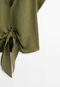 Top sans manches vert olive avec col en V et détail de nœud à l'avant en tissu texturé sur fond blanc.