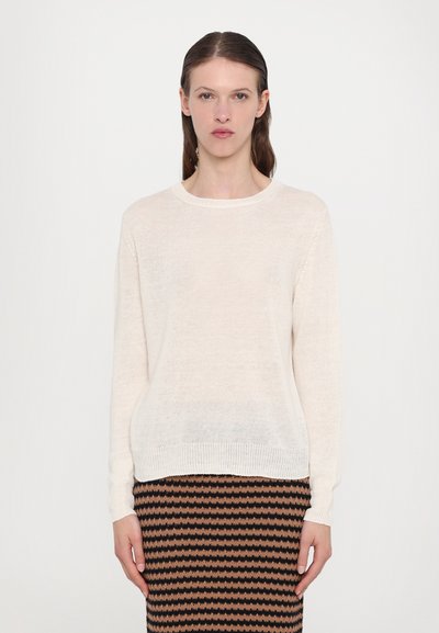 Light beige knit sweater with long sleeves and round neckline, paired with a patterned skirt featuring alternating brown and black zigzags.