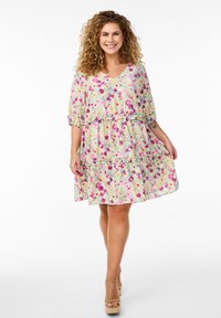 Robe à volants florale dans des teintes pastel, avec un col en V, des manches bouffantes et des coutures froncées. Le matériau semble léger et texturé.