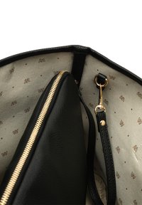 Interiér čiernej koženej kabelky s detailom zlatého zipsu, béžovým podšívkou s hnedým logom a vnútornou kapsou so záplatou.