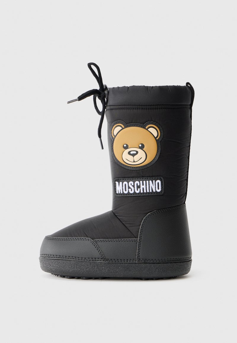 Black padded winter boot with a rounded toe, rubber sole, featuring a tan bear appliqué and white "Moschino" logo patch. Lace closure.