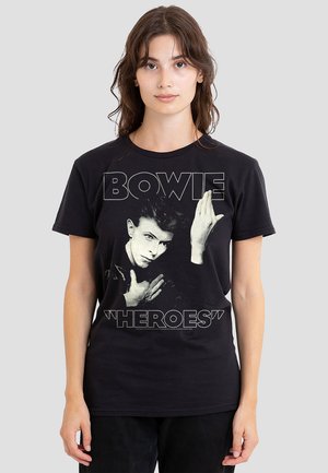 Black cotton t-shirt featuring a graphic of David Bowie with the text "BOWIE 'HEROES'" in white. The design has a classic fit and short sleeves.
