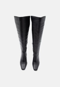 Μαύρες δερμάτινες μπότες μέχρι το γόνατο με εφαρμοστό σχέδιο, τετράγωνη μύτη και πλαϊνά φερμουάρ για εύκολη χρήση. Λείος υφής και ελάχιστες λεπτομέρειες.