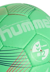 Grön Hummel Elite högpresterande matchboll med texturerad yta, mönstrade paneler, röda och blå accenter samt synlig trycklabel.