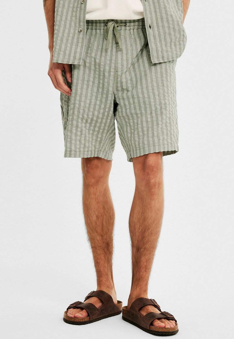 Ljusgröna randiga shorts i ett texturerat tyg, med elastisk midja med dragsko och sidofickor. Bruna sandaler fulländar looken.