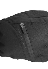 Sort softshell-handske med lynlås, en struktureret overflade og et fremtrædende "SOFT SHELL" mærke på siden for nem identifikation.