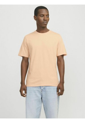 Kortærmet fersken T-shirt lavet af blødt bomuld, med rund halsudskæring og en afslappet pasform. Bæres med lyseblå denimjeans.