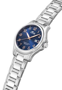 Montre à quartz avec un cadran bleu, bracelet en acier inoxydable argenté, index des heures en or rose, affichage de la date et étanchéité jusqu'à 10 bars.