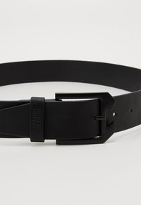 Svart lærbelte med matt finish, utstyrt med et rektangulært metallspenne og justeringshull, som viser et enkelt og elegant design.
