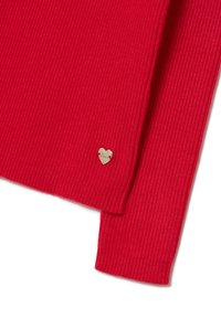 Roter gerippter Pullover mit einem kleinen goldenen Herzanhänger mit Gravur. Weicher Stoff und taillierter Schnitt.