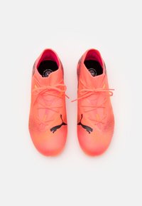 Scarpe da ginnastica rosa con tomaia in rete, finitura testurizzata, accenti del logo neri e lacci piatti. Design minimalista con punte arrotondate.