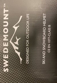 Zwarte verpakking met witte tekst die "SWEDEMOUNT" en "ONTWORPEN VOOR HET BUITENLEVEN" vermeldt. Bevat een afbeelding van bergen en een stippenpatroon.