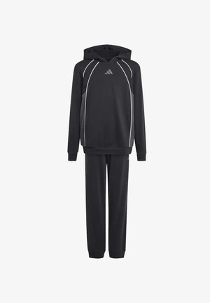 Twee jonge mensen die zwarte hoodies en bijpassende broeken dragen, staan rug aan rug en kijken in tegenovergestelde richtingen.