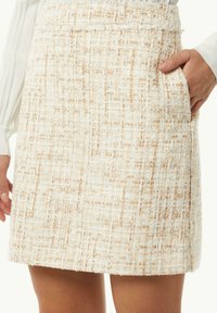 Geweven A-lijn rok in crème met een textuurpatroon. Voorzien van zijzakken en een gladde tailleband. Materiaal heeft een lichte glans.
