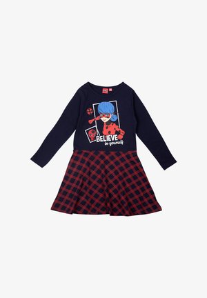 Abito lungo a maniche con stampa di un personaggio dei cartoni animati in navy e la scritta "CREDI in te stesso." La gonna presenta un motivo a quadretti rossi e navy.