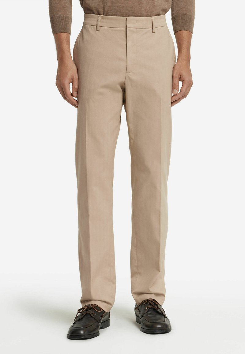 Beige skräddarsydda byxor med rak benform, med platt front och bälteshällor, matchade med mörka snörskor.