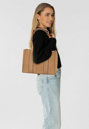 Braune Handtasche mit strukturiertem Oberflächenmaterial, doppelten Obergriffen und vertikaler Gestaltung. Kombiniert mit einem schwarzen Pullover und heller Jeans.