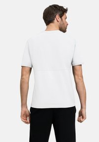 Koszulka z krótkim rękawem, jasnoszara, wykonana z miękkiego materiału, z detalem szwu na plecach, w połączeniu z czarnymi spodniami.