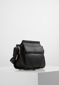 Black textured leather handbag featuring a fold-over flap, adjustable strap, and gold-tone hardware accents. Compact rectangular shape.