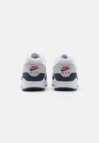 Nike Air-sneakers i vitt, grått och marinblått. Har en vadderad krage, mesh-övre och röda logotypdetaljer. Sula designad för komfort och stöd.