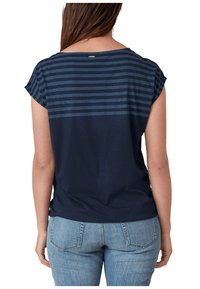 Camiseta de color azul marino de manga corta, con un patrón a rayas en la parte superior de la espalda, hecha de una tela suave. Lleva puesta un pantalón vaquero azul.