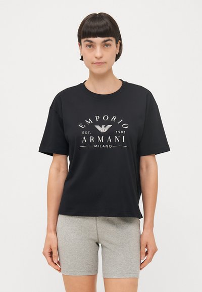 Czarny bawełniany t-shirt z krótkimi rękawami, z białym nadrukowanym logo i tekstem. Połączony z szarymi prążkowanymi szortami. Casualowy look.