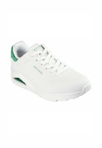 Weißer Sportschuh mit perforiertem Design, grüner Wildleder-Hackenakzent, schnürteller und luftgepolsteter Sohle. Markenname "Skechers" sichtbar.