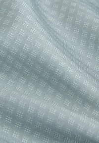 Tissu texturé bleu clair arborant un motif à carreaux avec de petits carrés en relief, créant un design subtil mais complexe.
