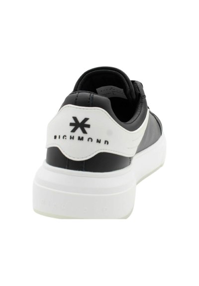 Sneaker bianco e nero con tomaia in pelle liscia, tallone a contrasto, suola bianca spessa e dettaglio del logo sul retro.