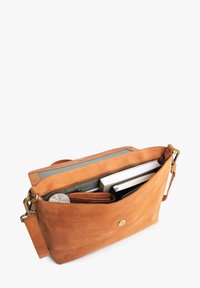 Leder-Umhängetasche in Hellbraun, mit Reißverschluss, verstellbarem Riemen, Innenfächern und ausgestattet mit einem Notizblock, einer Brieftasche und einem Getränk.