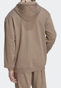 Brun, texturerad hoodie med huva och dragsko, långa ärmar och ribbade muddar. Har en avslappnad passform med en minimalistisk design.