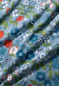 Tissu avec un fond bleu et un motif floral et d'oiseaux. Les couleurs comprennent le rouge, le vert et le blanc. Texture lisse, légèrement froissée.
